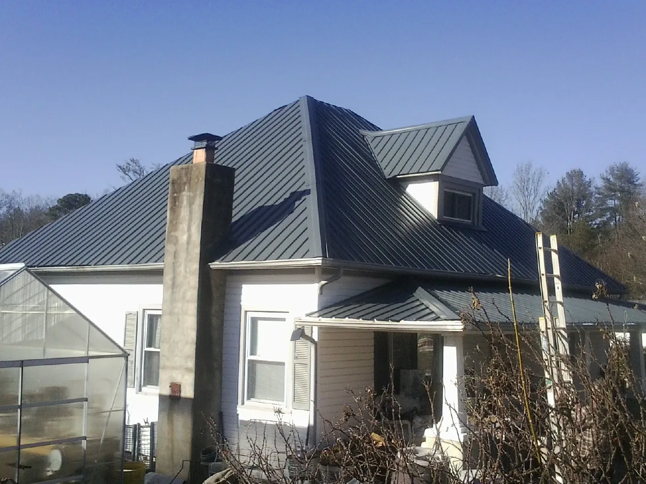 Dark blue standing seam metal roof on a white farmhouse with dormer — Slate & Tile Roof Repair by Roofing Brothers in Tea