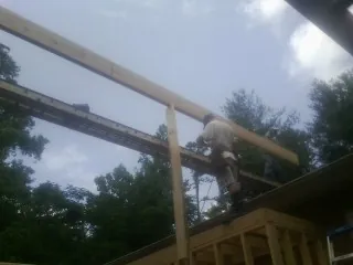 Carpenter setting a ridge beam over a new addition frame — Ice Dam Removal by Roofing Brothers in Tea