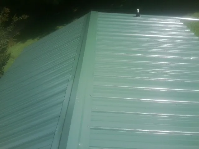 New green metal panels meeting at the ridge of a roof — Flat Roof Repair work by our crew in Tea