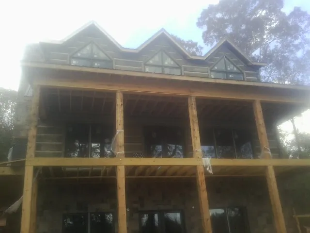 Dormers and porch framing on a large log home under construction — Roof Coating work by our crew in Tea