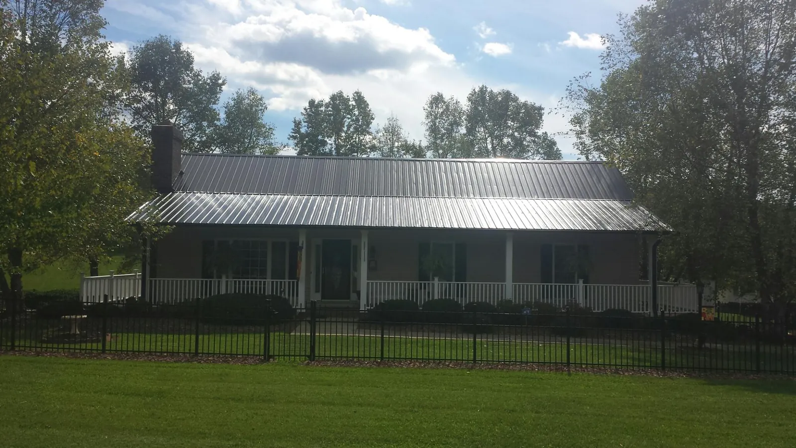 Gray metal roof on a brick ranch with a full width front porch — Gutter Guard Installation work by our crew in Tea