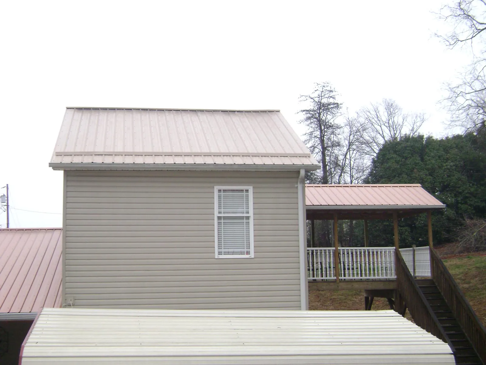Tan metal roofs on a two story addition and attached porch, from a Roof Replacement job in Tea