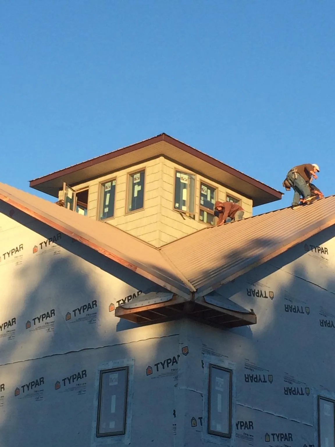 Roofers working around a rooftop cupola on a new metal roof at sunset — Roof Waterproofing in Tea by Roofing Brothers